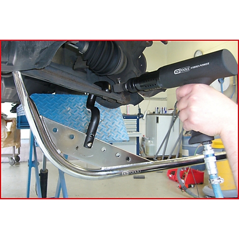 Person nutzt Druckluftschrauber an einem Autoteil. Im Vordergrund ein Chrombügel.